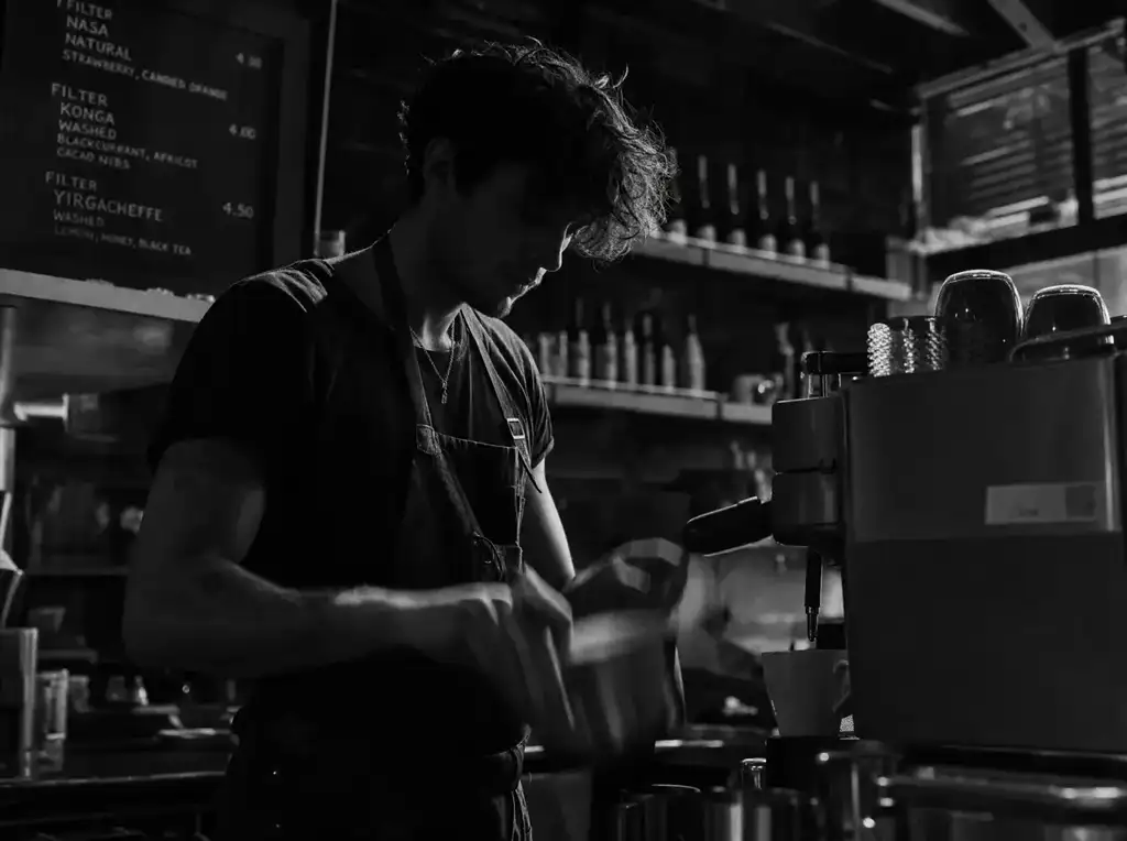 Barista při práci za tmavým barem